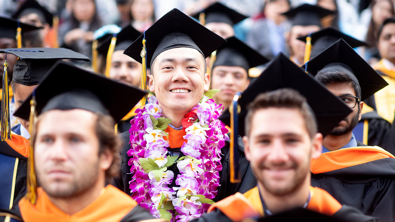 Student in lei in crowd of other graduates