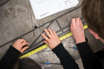 Students measuring a steel bridge component