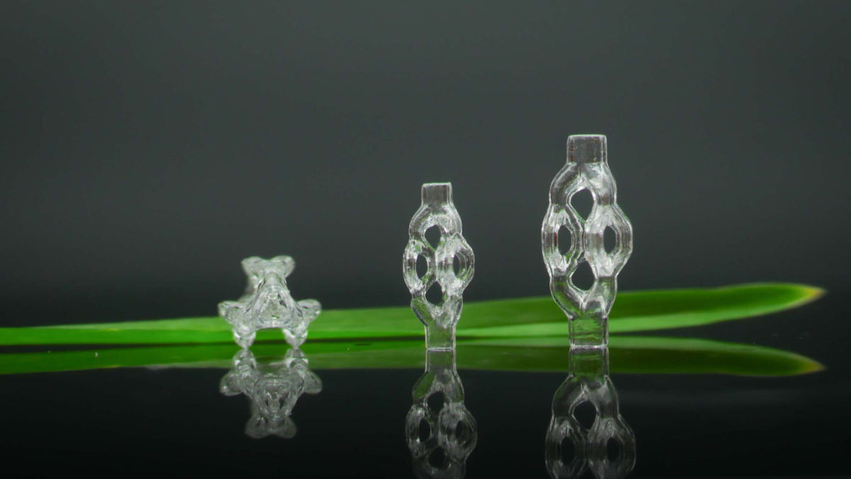 3D-printed, trifurcated microtubule models, displayed beside a blade of grass