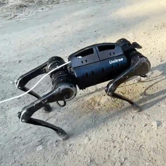 A quadruped robot stands on gravel.