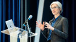 Jennifer Doudna speaks on stage while standing behind a podium and laptop.